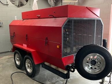 A large red industrial generator or compressor on wheels indoors.