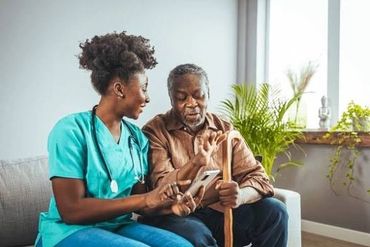 A nurse shows an elderly man something on a smartphone.