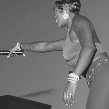 Black and white side view of a woman performing with a microphone.