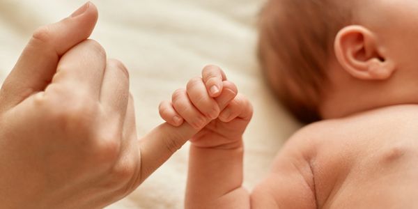 Baby holding womens finger