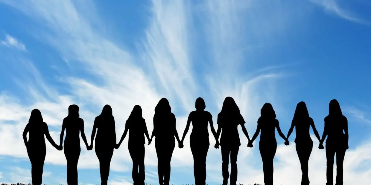 Silhouettes of people holding hands against a blue sky.