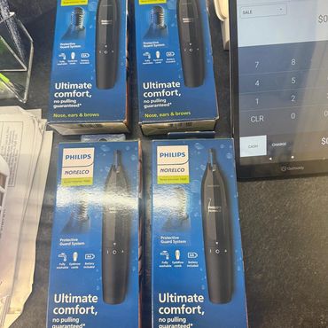 Four Philips Norelco nose trimmers displayed near a payment terminal.