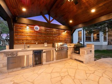 Outdoor kitchen with grill and wooden ceiling.