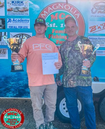 Two men holding trophies at a fishing event.