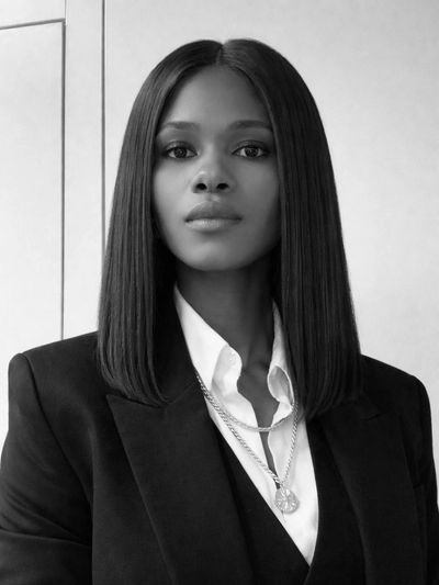Confident woman in a sleek black suit and white shirt.