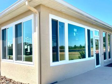 New house exterior with large white-framed windows and a glass door.
