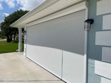 Closed white garage door on a sunny day with outdoor light fixtures.