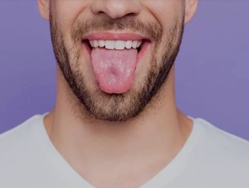 Man with beard sticking out his tongue against a purple background.