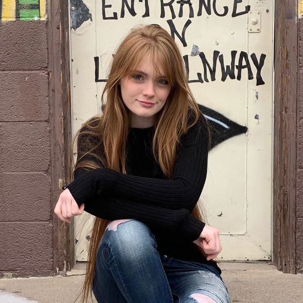 A charismatic Maddy on the steps at Ernie November. Long red hair, blue jeans, adorable smile.