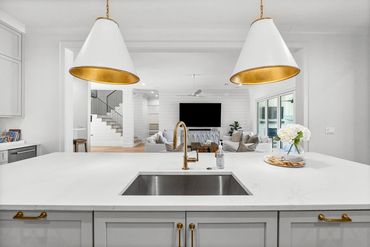 Modern kitchen island with gold fixtures and white marble countertop.