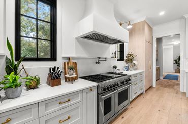 Modern kitchen with stainless steel stove, white cabinets, and gold hardware.
