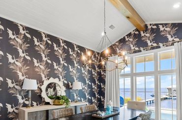 Chic dining room with bird-themed wallpaper and waterfront view.