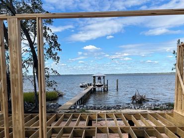 Wooden house framing overlooking a lake with a dock and boat.
