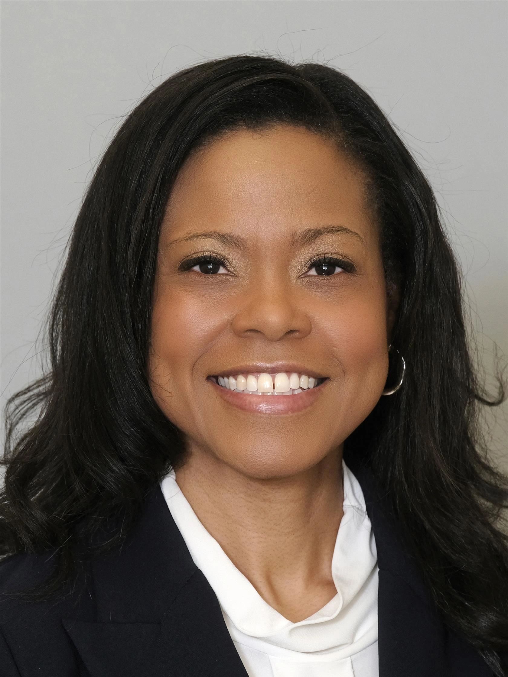 Smiling woman with dark hair and hoop earrings.