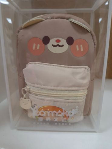 Cute bear-themed small backpack with front zipper pocket inside a clear box.