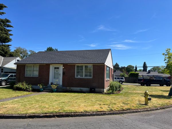 Small brick house with a well-kept lawn on a sunny day.