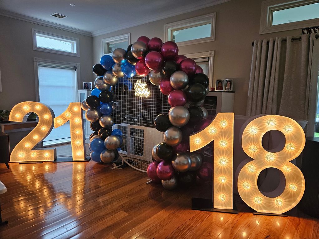 Illuminated birthday numbers 21 and 18 with balloon arch.