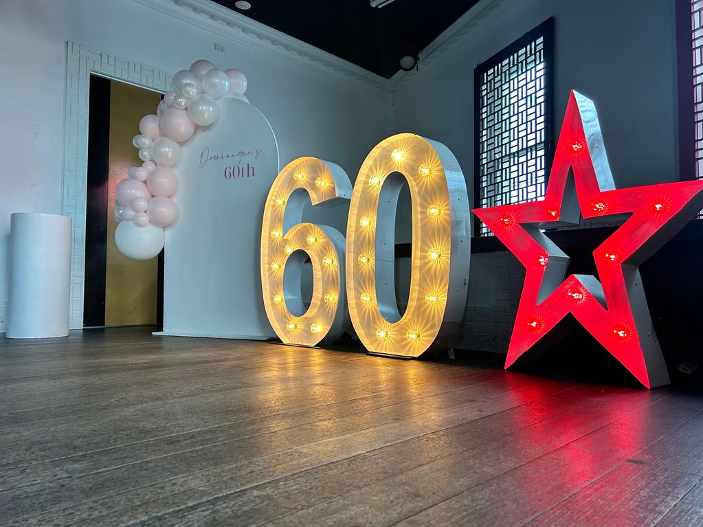 Decorated 60th birthday display with lights and balloons.