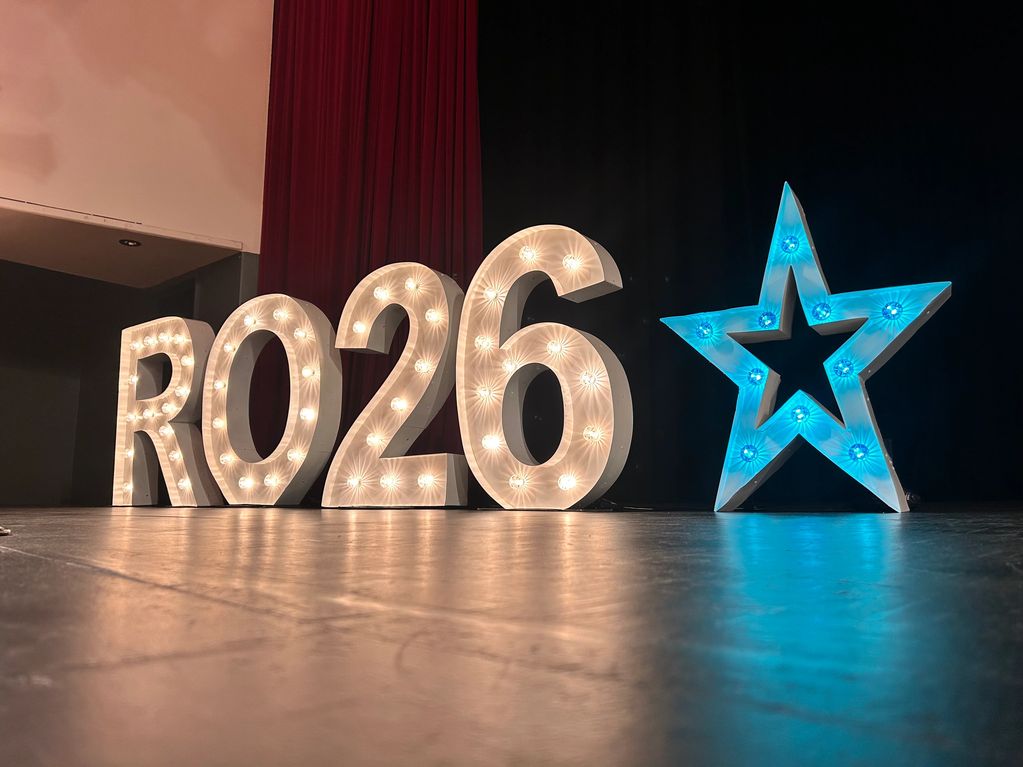 Illuminated RO26 sign with a blue star beside it on stage.