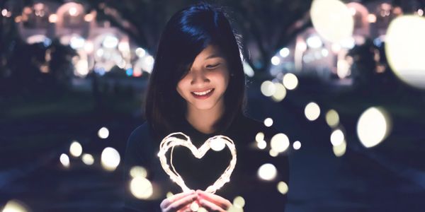 Woman holding glowing heart, smiling