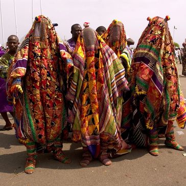 Four people in colorful, patterned costumes with head coverings at a cultural event.