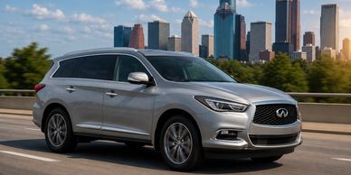 Silver Infiniti SUV driving on a highway with city skyline in the background.