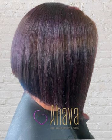 Sleek angled bob haircut with subtle purple highlights on straight hair.