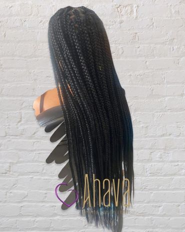 Long, neatly braided black hair displayed against a white brick wall.