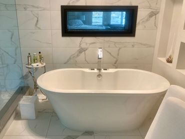 Custom bathroom, featuring a freestanding bathtub with a deck mounted faucet.