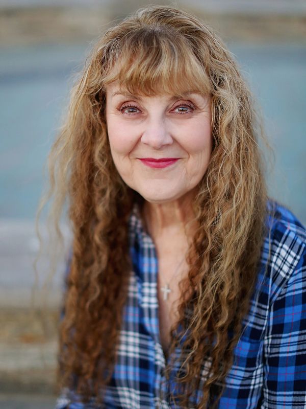 Photo of Dr. Rees. Woman with long wavy hair wearing plaid shirt.