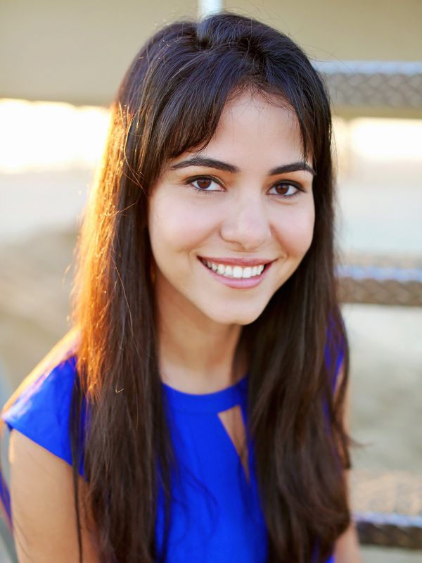 Photo of Dr. Pouroushasb. Woman with long hair wearing blue top and beautiful smile.