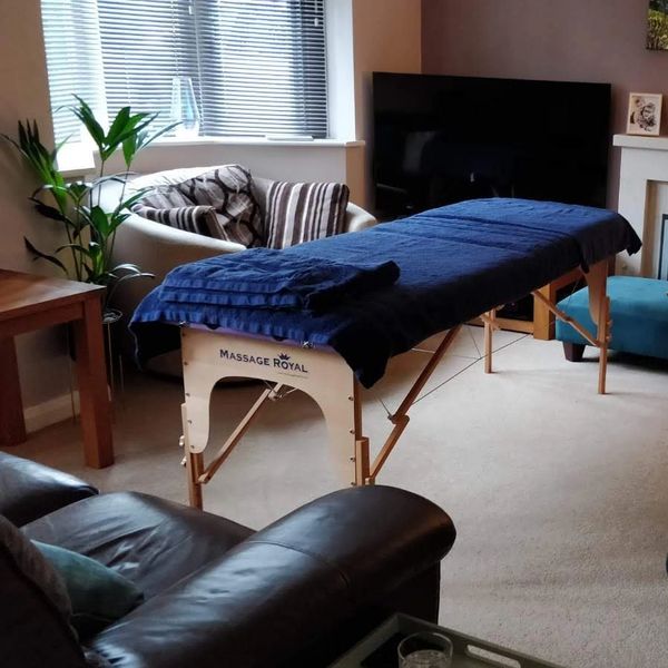 Luxury wooden massage table covered in fresh, soft, Egyptian cotton towels in a client's lounge
