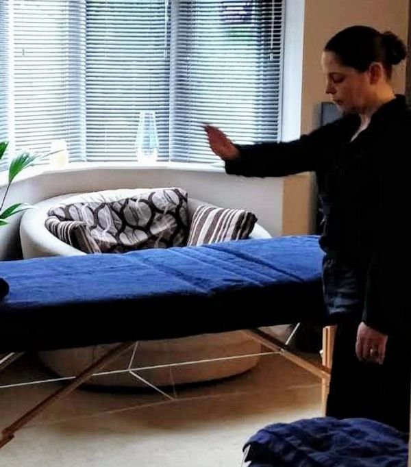 Jo setting up - standing over the massage table placing Reiki energy into the space