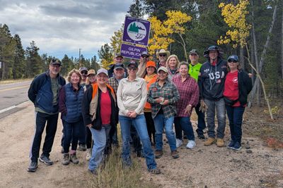 Group photo of volunteers by a highway with autumn trees and a Gilpin Republican sign.