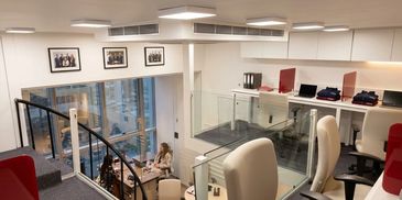 Modern office space with glass walls and comfortable seating.