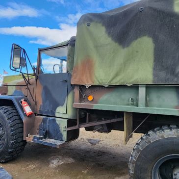 Military truck with camouflage paint and covered cargo area.