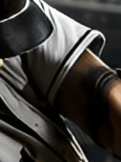 Close-up of a person's arm with a tattoo and grey shirt.