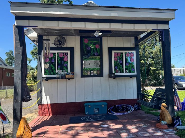 Small outdoor cafe with decorated windows and a garden swing under a clear blue sky.