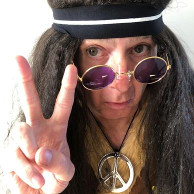 Person in hippie costume making peace sign.