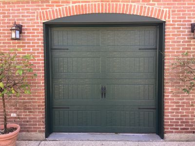 Dark green garage door installed in a red brick home.