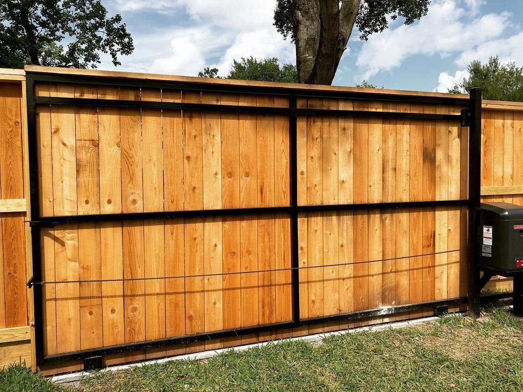 Sliding gate motor installed on a wooden fence with metal frame