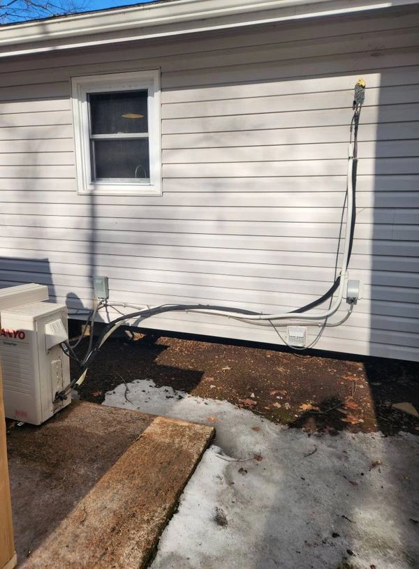Exterior house wall with electrical cables and a small window.