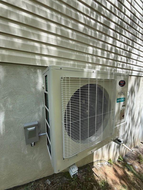 Outdoor Fujitsu air conditioning unit mounted on house exterior.