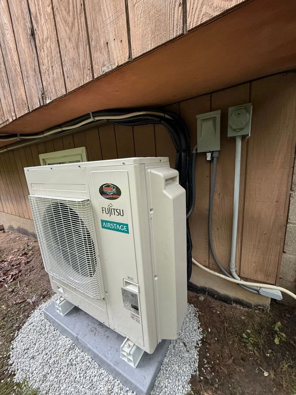 Outdoor Fujitsu Airstage air conditioning unit installed on a concrete base.