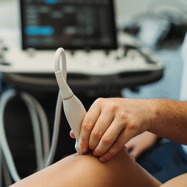 Hand holding ultrasound probe on a patient's knee.