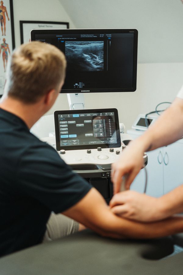 Medical professional performing an ultrasound on a patient's arm.