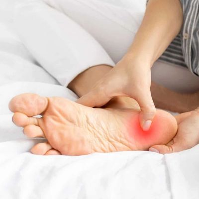 Person pressing the painful red area on their foot's sole.