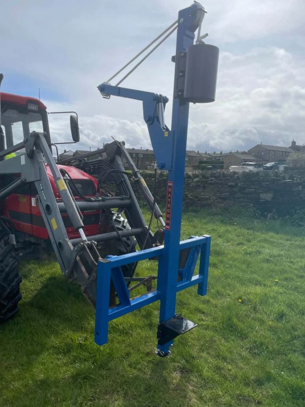Blue farm equipment attached to a tractor in a grassy field.