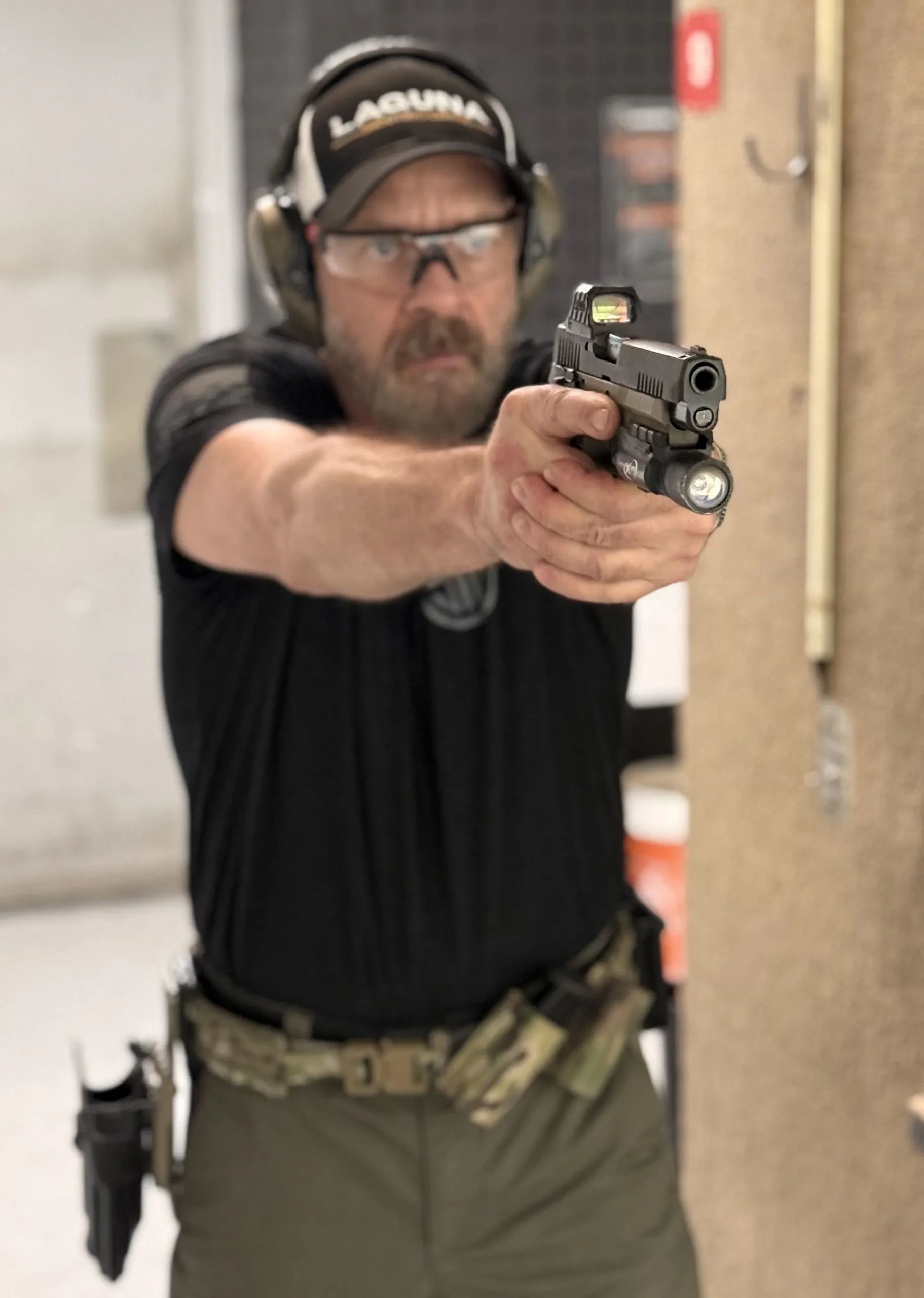 Man aiming a handgun at a shooting range.
