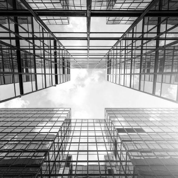 Looking up between towering glass skyscrapers on a cloudy day.